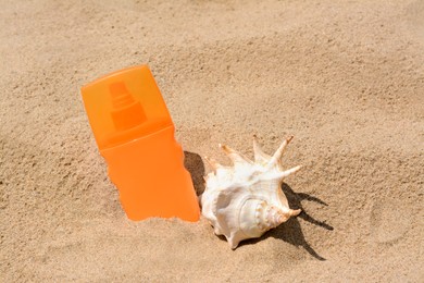 Photo of Bottle with sun protection spray and seashell on sandy beach