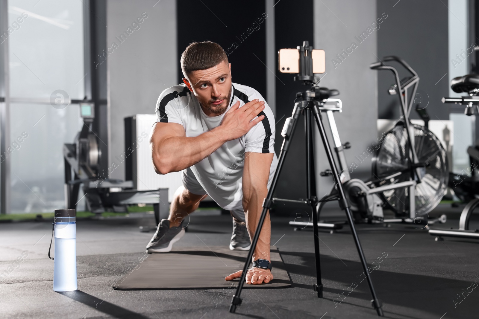 Photo of Trainer streaming online workout with phone at gym