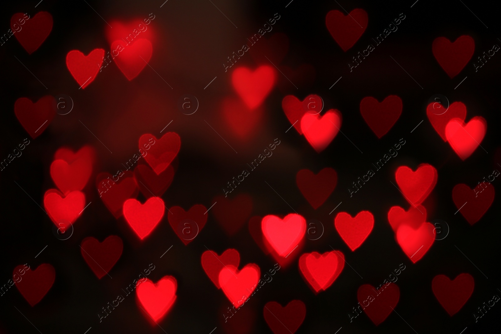 Photo of Blurred view of red heart shaped lights on black background