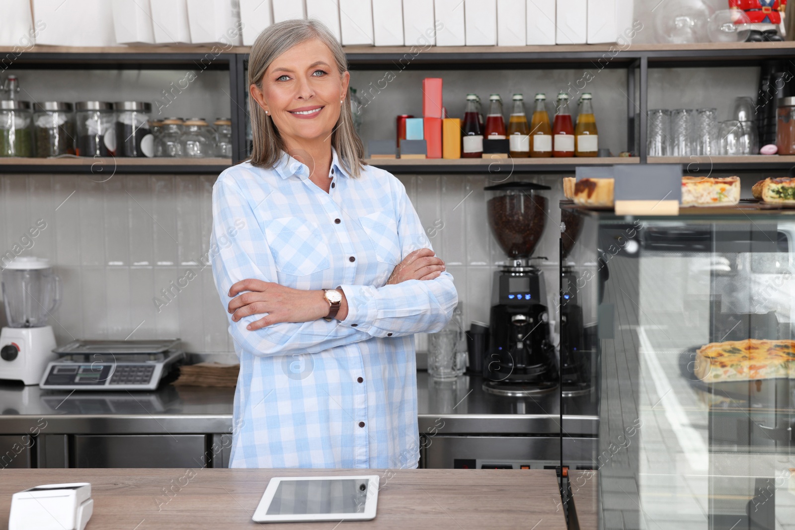 Photo of Portrait of happy business owner at cashier desk in her cafe