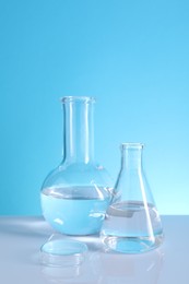 Photo of Laboratory analysis. Glass flasks on table against light blue background