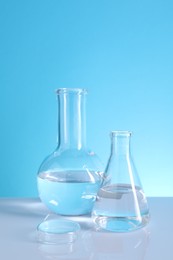 Laboratory analysis. Glass flasks on table against light blue background