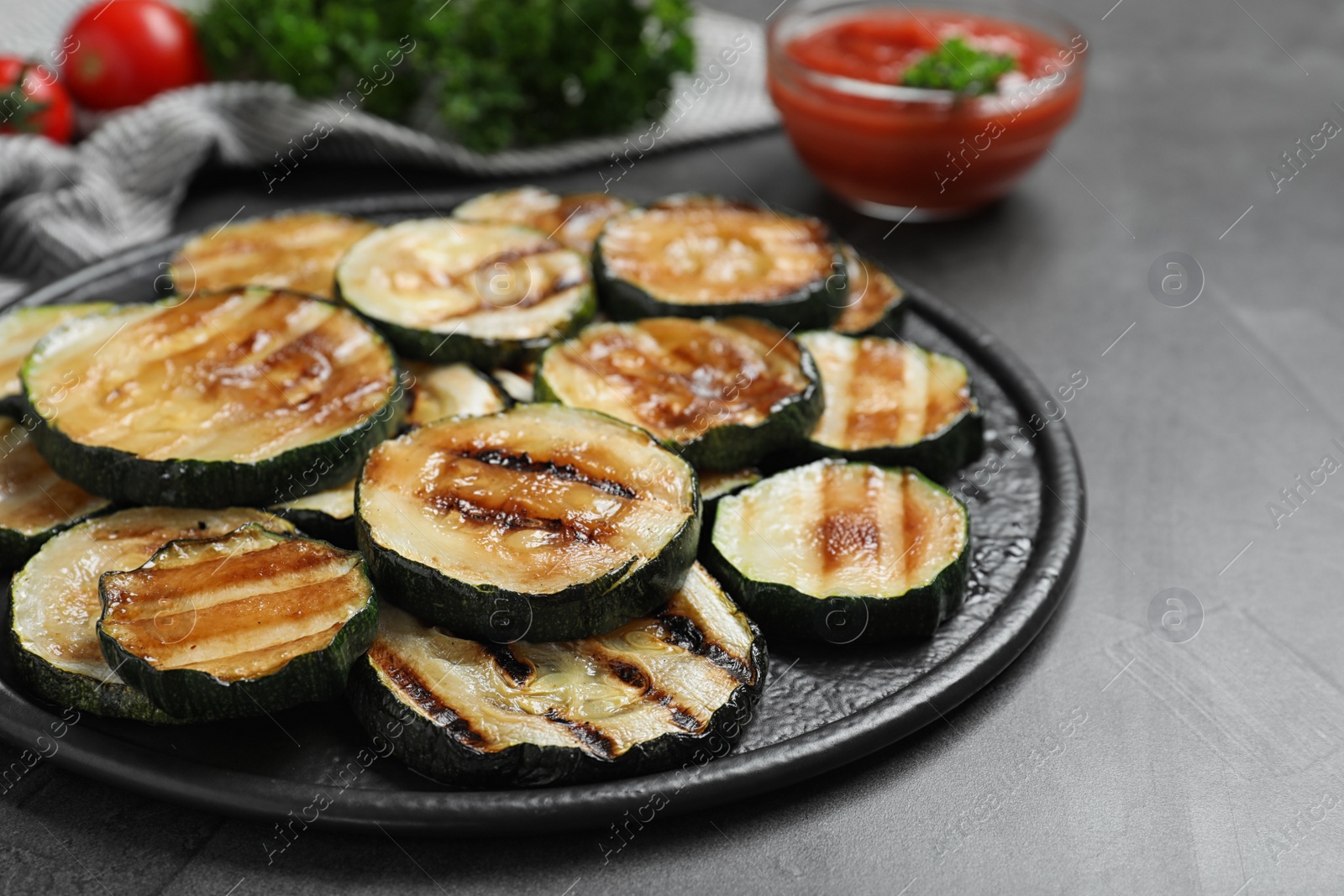 Photo of Delicious grilled zucchini slices served on grey table