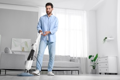 Photo of Man cleaning floor with steam mop at home. Space for text