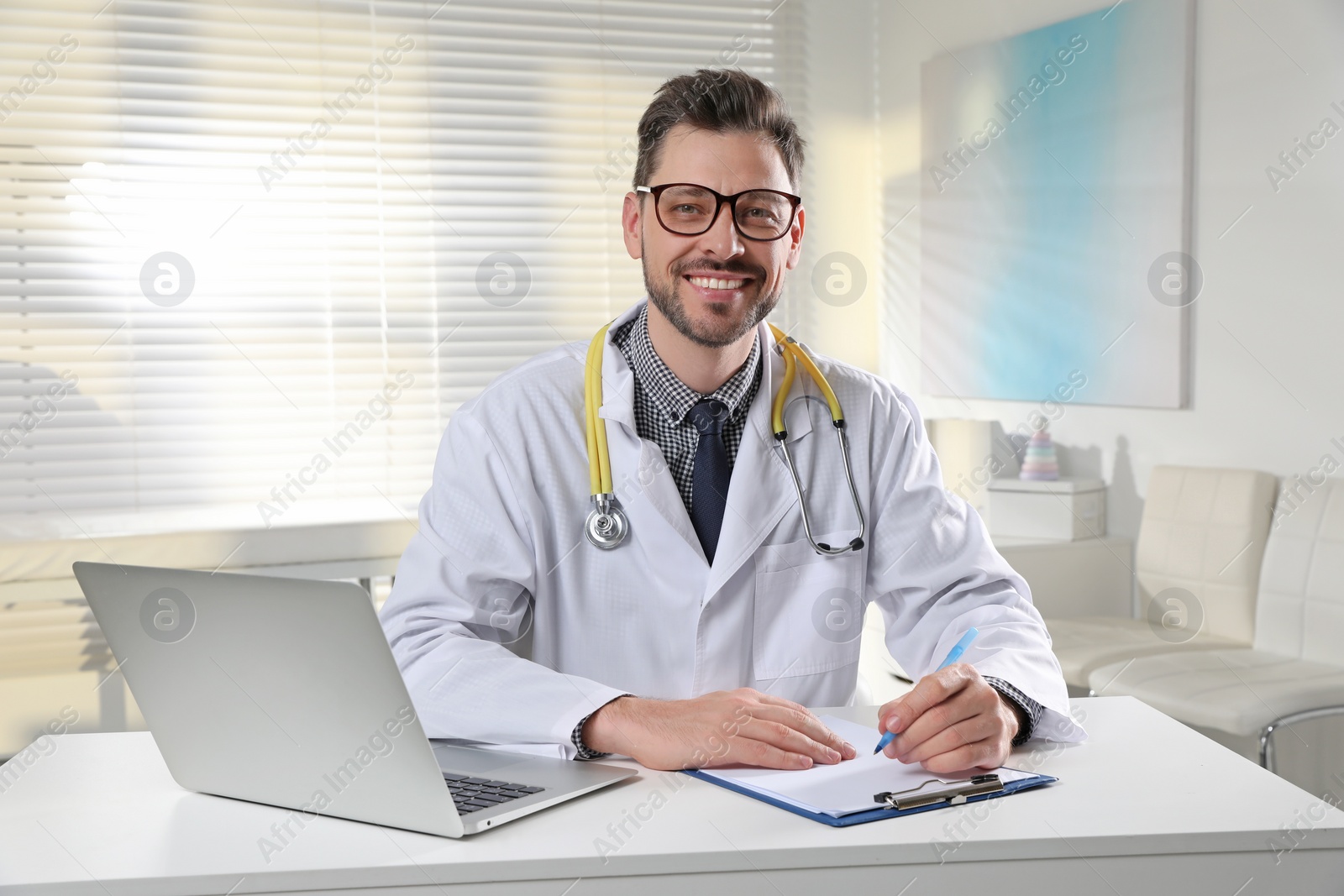 Photo of Pediatrician with stethoscope at table in clinic