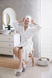 Photo of Beautiful young woman wearing soft white robe in bathroom