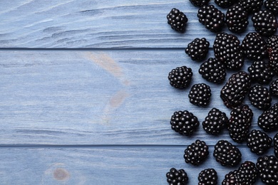 Fresh ripe blackberries on blue wooden table, flat lay. Space for text