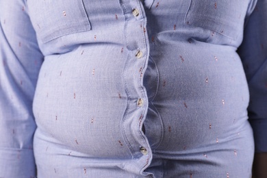 Photo of Overweight woman in tight shirt, closeup. Obesity and weight loss