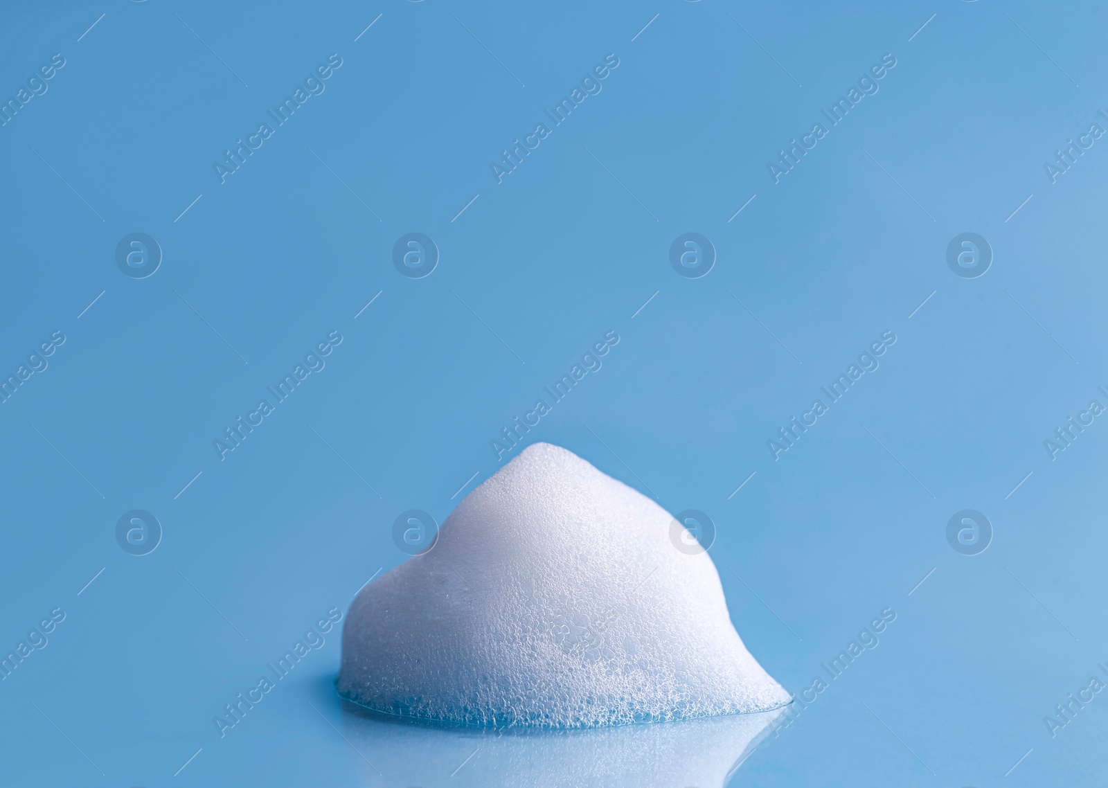 Photo of Fluffy white foam on light blue background, space for text