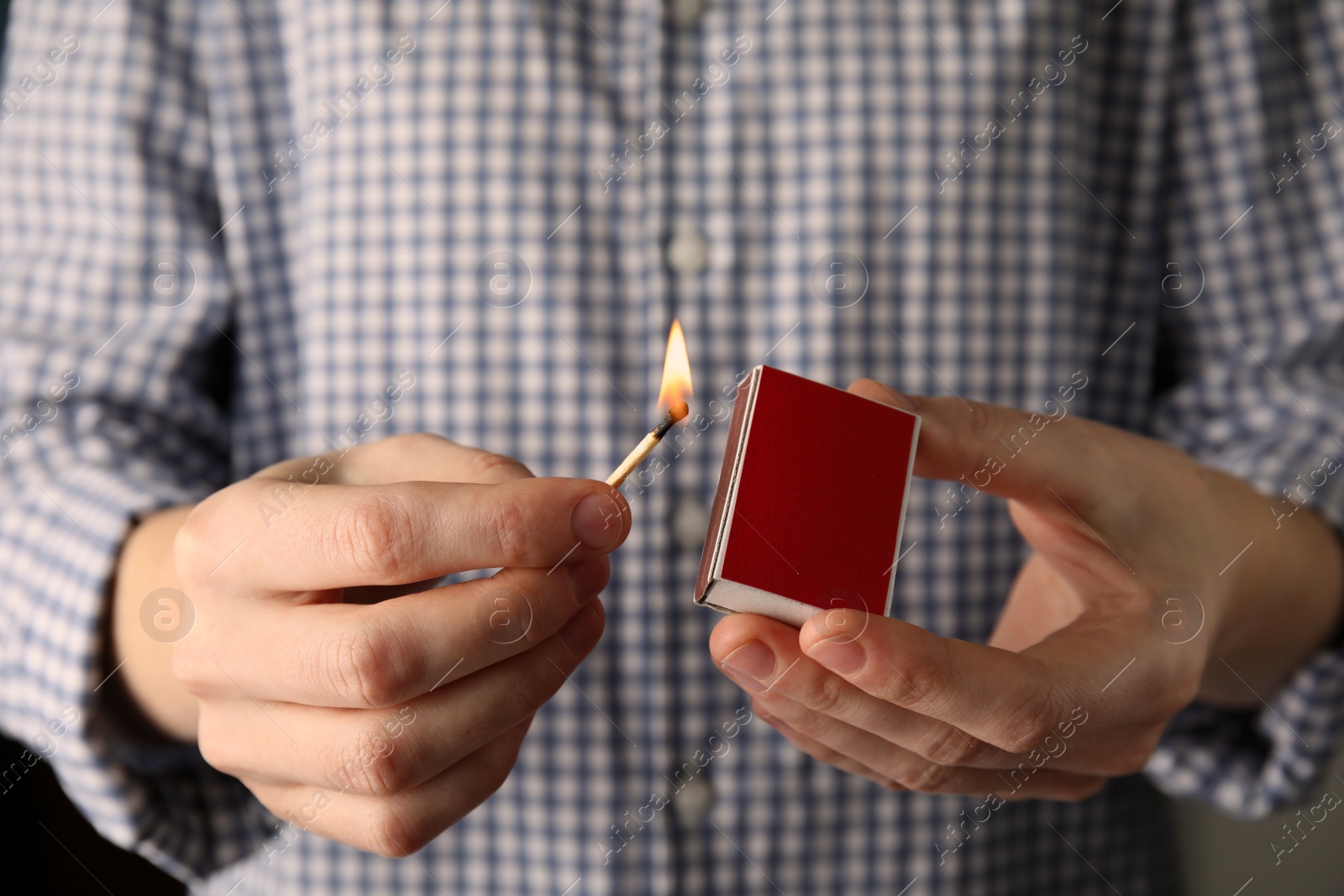 Photo of Man with box and burning match, closeup