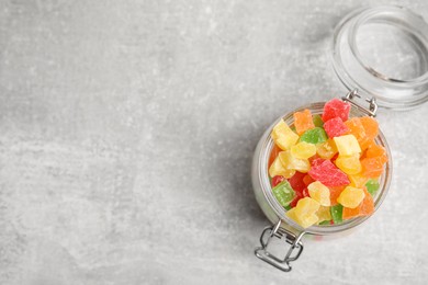 Photo of Mix of delicious candied fruits in jar on light grey table, top view. Space for text