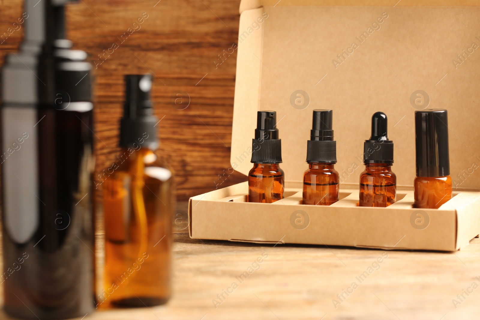 Photo of Bottles with oil in box on wooden table. Natural cosmetics