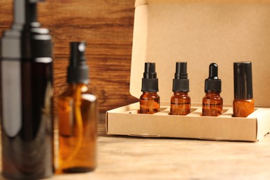 Photo of Bottles with oil in box on wooden table. Natural cosmetics