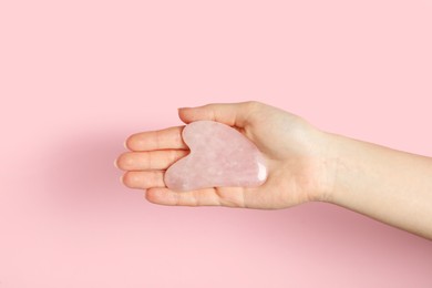 Photo of Woman with rose quartz gua sha tool on pink background, closeup