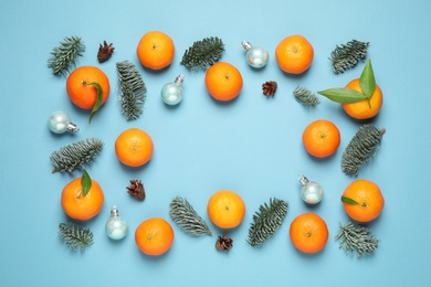 Frame made of Christmas balls and tangerines on light blue background, flat lay
