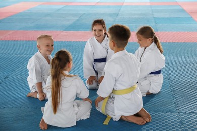 Photo of Group of children in kimono sitting on tatami after karate practice