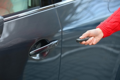 Closeup view of woman opening car door with remote key