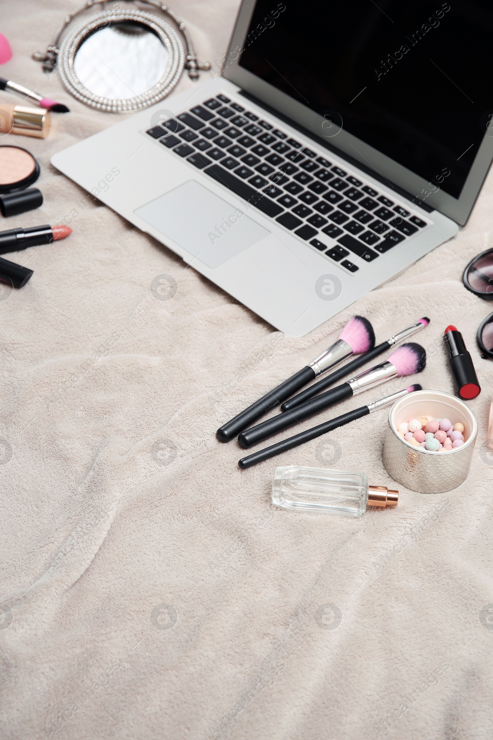 Photo of Composition with laptop and makeup products for woman on fabric