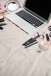 Photo of Composition with laptop and makeup products for woman on fabric