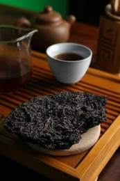 Photo of Broken disc shaped pu-erh tea on wooden tray