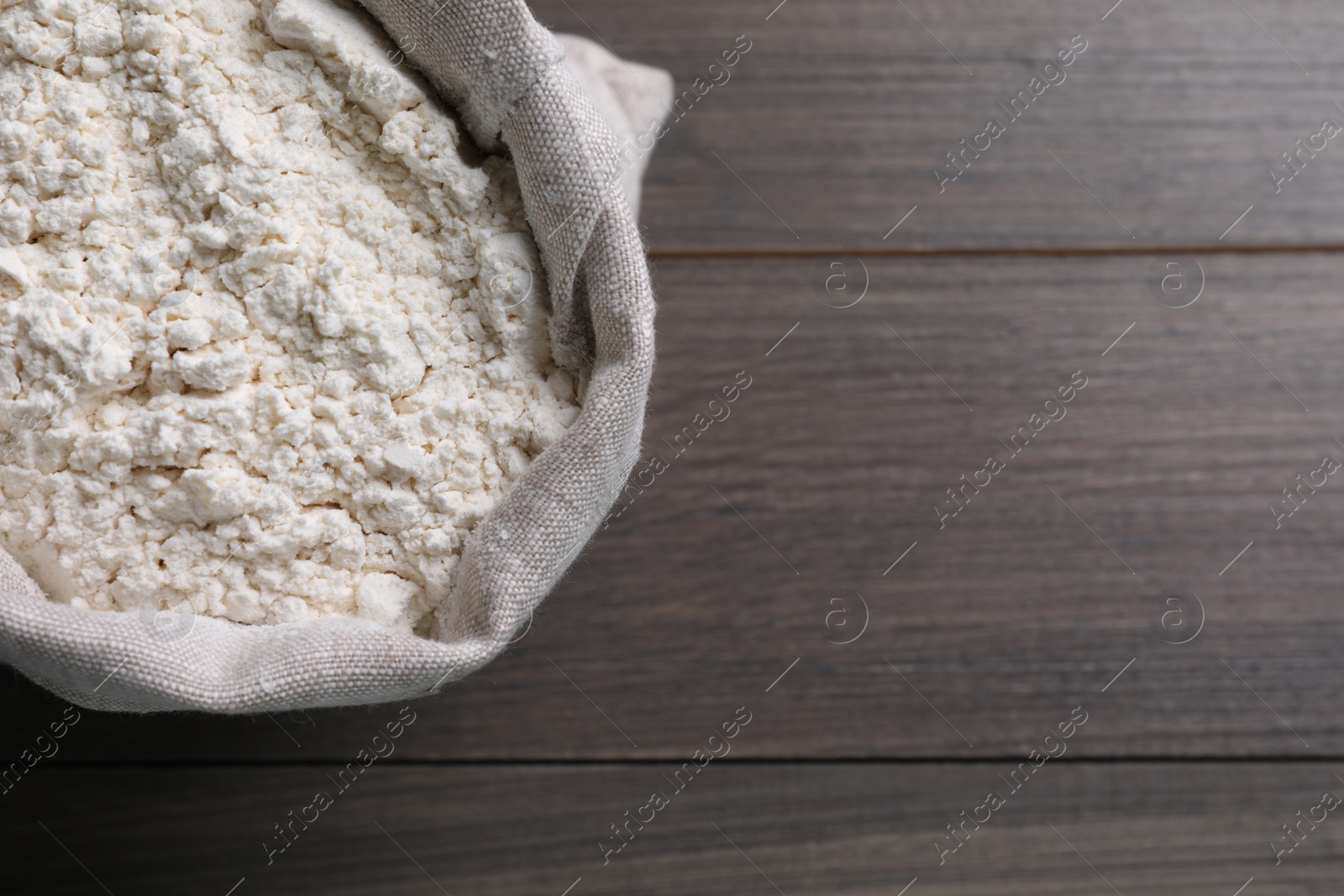 Photo of Sack with flour on wooden background, top view. Space for text