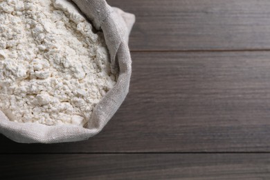 Sack with flour on wooden background, top view. Space for text