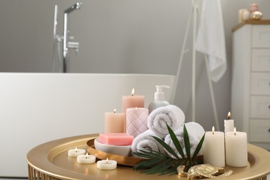 Photo of Composition with different spa products, burning candles and palm leaf on table in bathroom