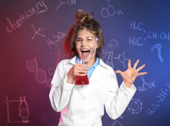 Photo of Emotional pupil holding conical flask against blackboard with chemistry formulas
