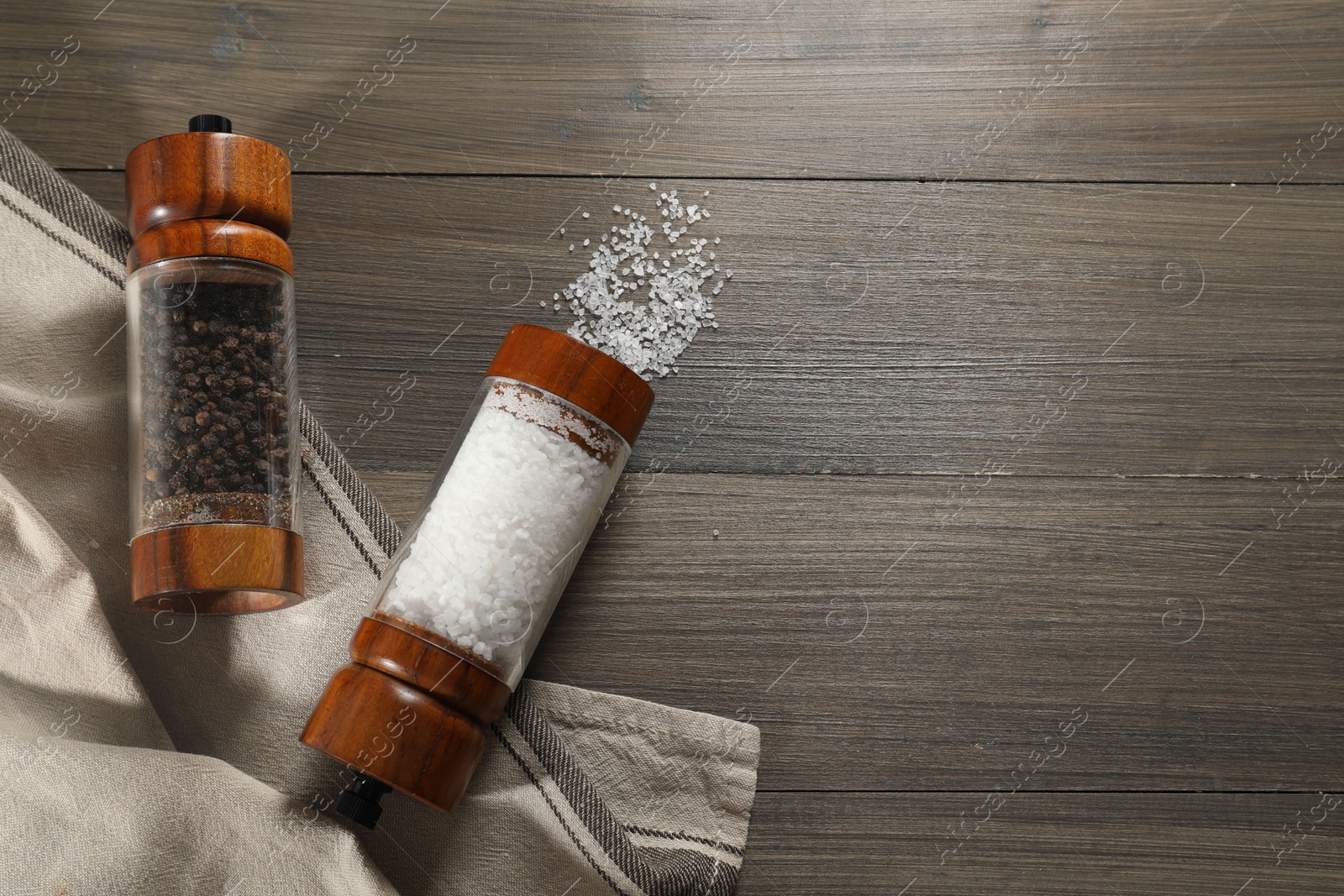 Photo of Salt and pepper shakers on wooden table, flat lay. Space for text