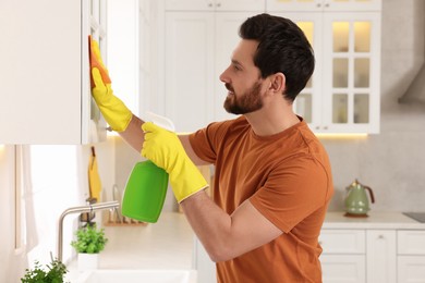 Photo of Spring cleaning. Man tidying up kitchen at home