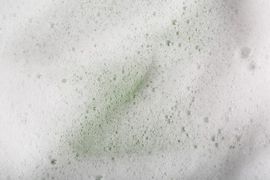 Photo of White fluffy foam on green background, top view