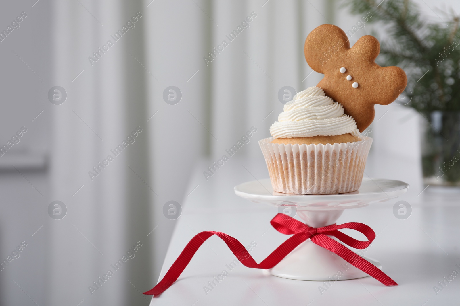 Photo of Tasty Christmas cupcake with cream and gingerbread man cookie on white table, space for text