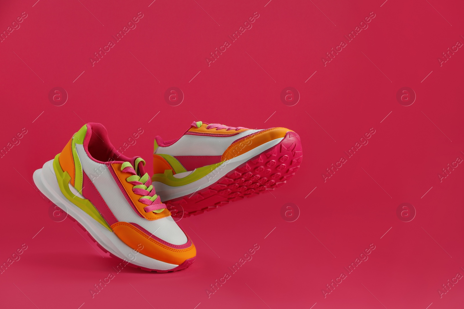 Photo of Pair of stylish colorful sneakers levitating on pink background, space for text