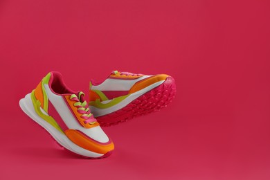 Pair of stylish colorful sneakers levitating on pink background, space for text