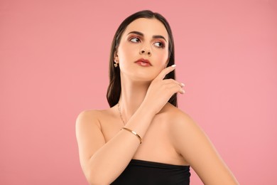 Beautiful woman with elegant jewelry on pink background