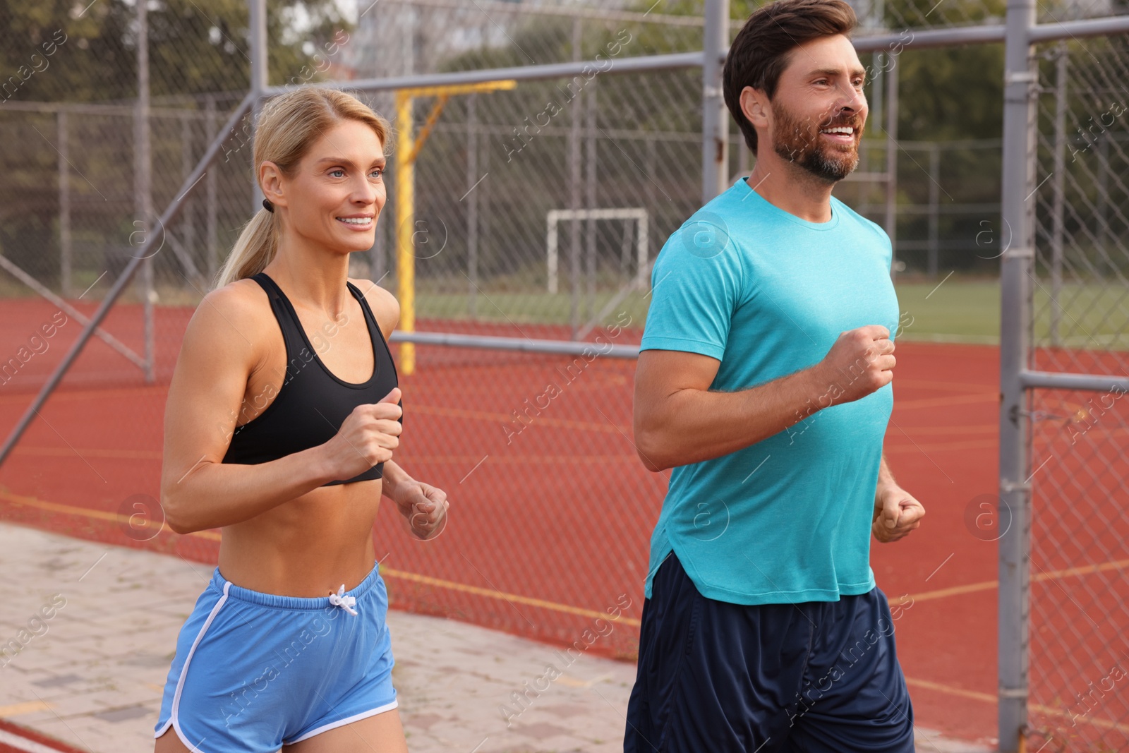 Photo of Healthy lifestyle. Happy sporty couple running at stadium