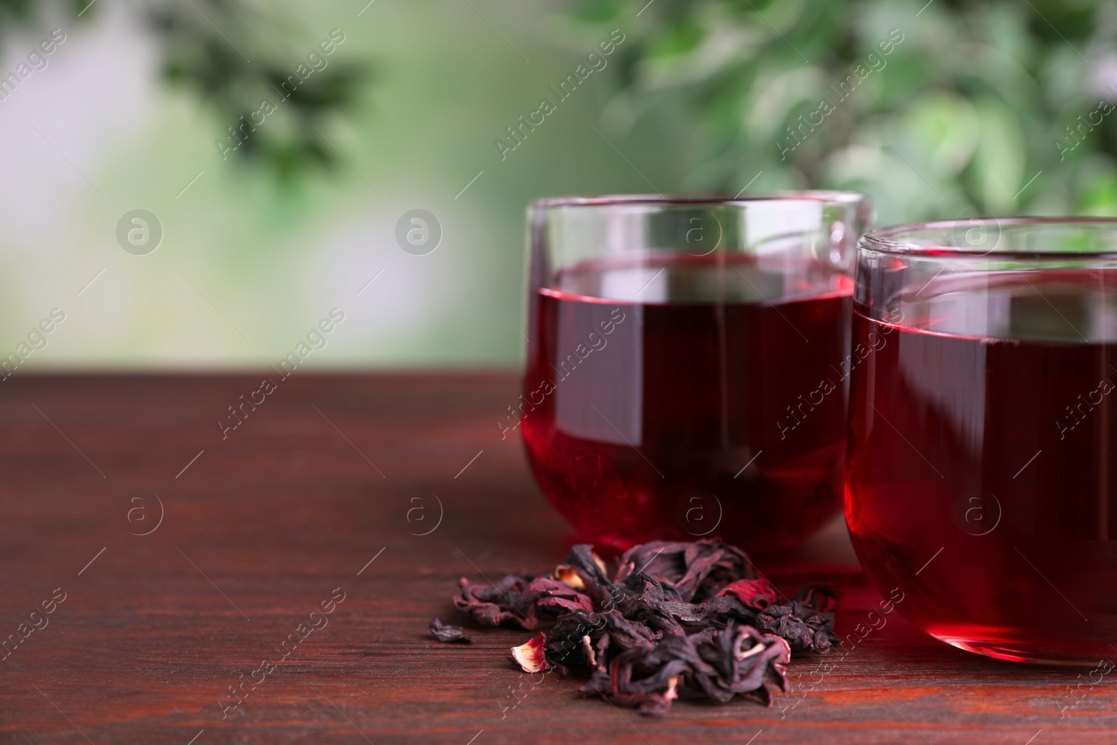 Photo of Freshly brewed hibiscus tea on wooden table, closeup. Space for text