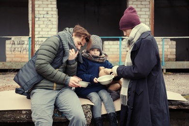 Photo of Poor young family with bread on dirty street