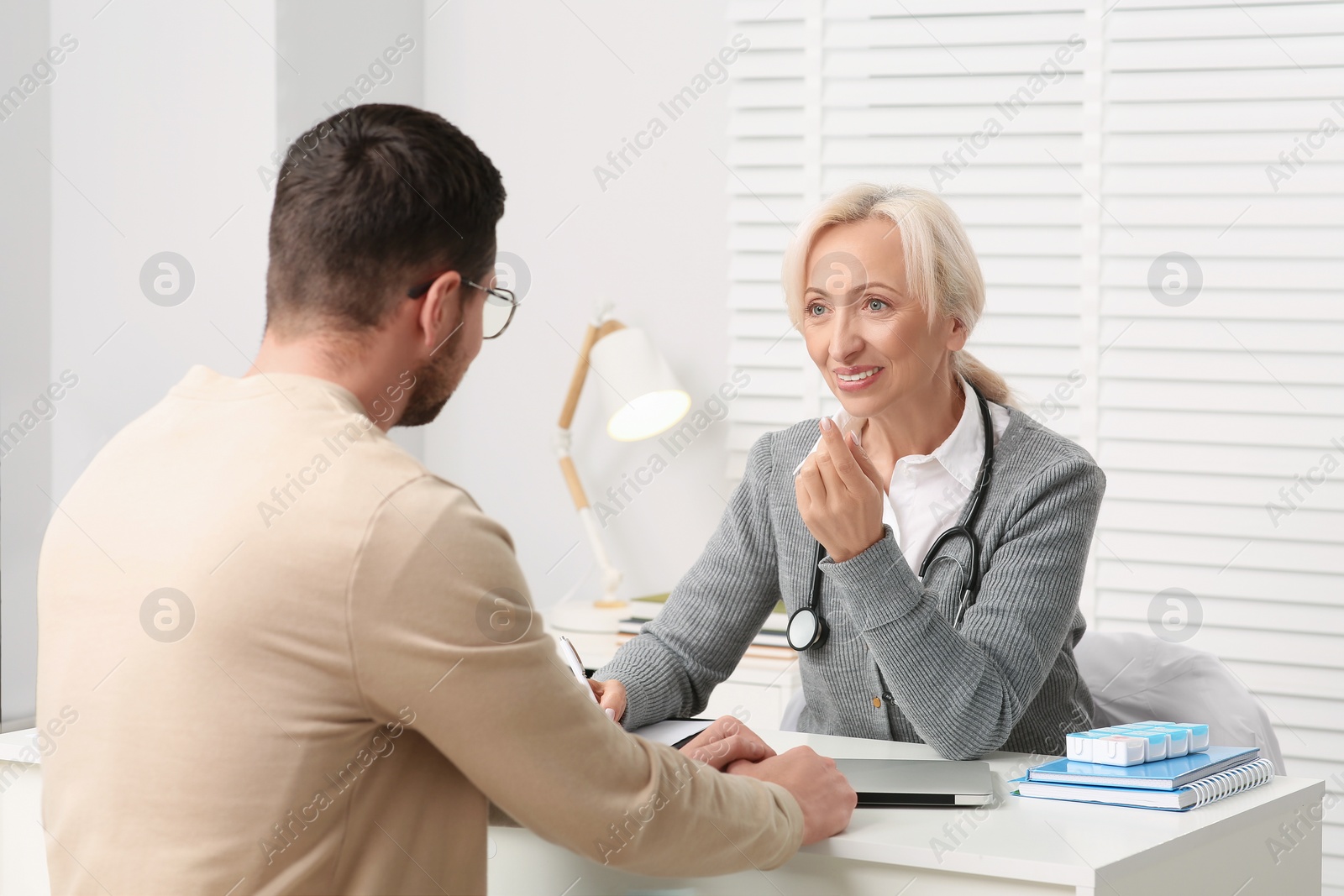 Photo of Doctor consulting patient at white table in clinic