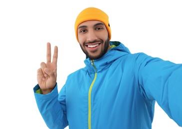 Smiling young man taking selfie and showing peace sign on white background