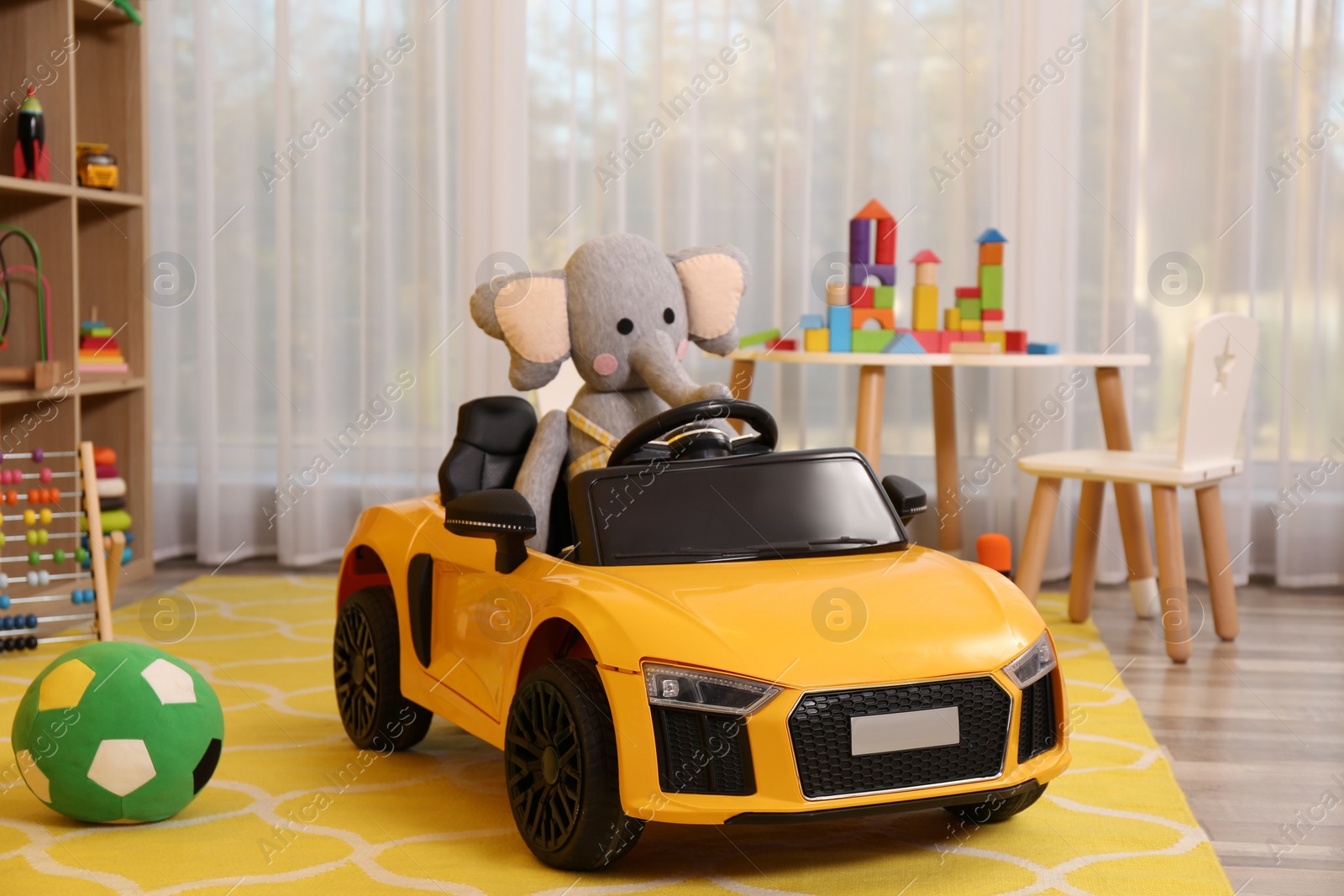 Photo of Child's electric car with toy elephant in playroom