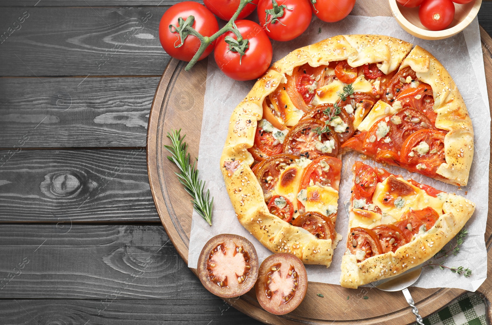 Photo of Tasty galette with tomato and cheese (Caprese galette) on black wooden table, top view. Space for text