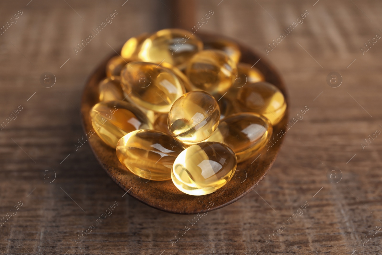 Photo of Spoon with cod liver oil pills on table, closeup