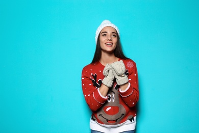 Photo of Young woman in Christmas sweater and knitted hat on color background