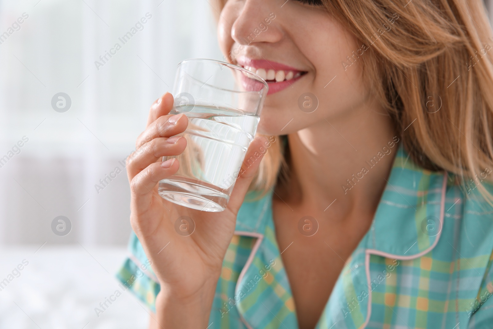 Photo of Young woman drinking water from glass indoors, closeup