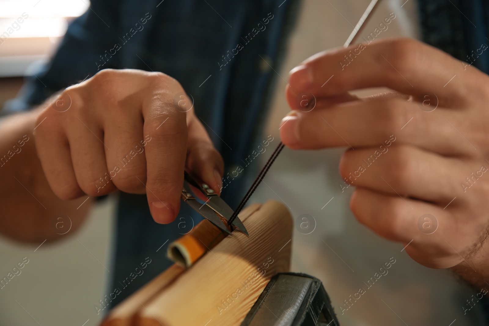 Photo of Man sewing piece of leather in workshop, closeup