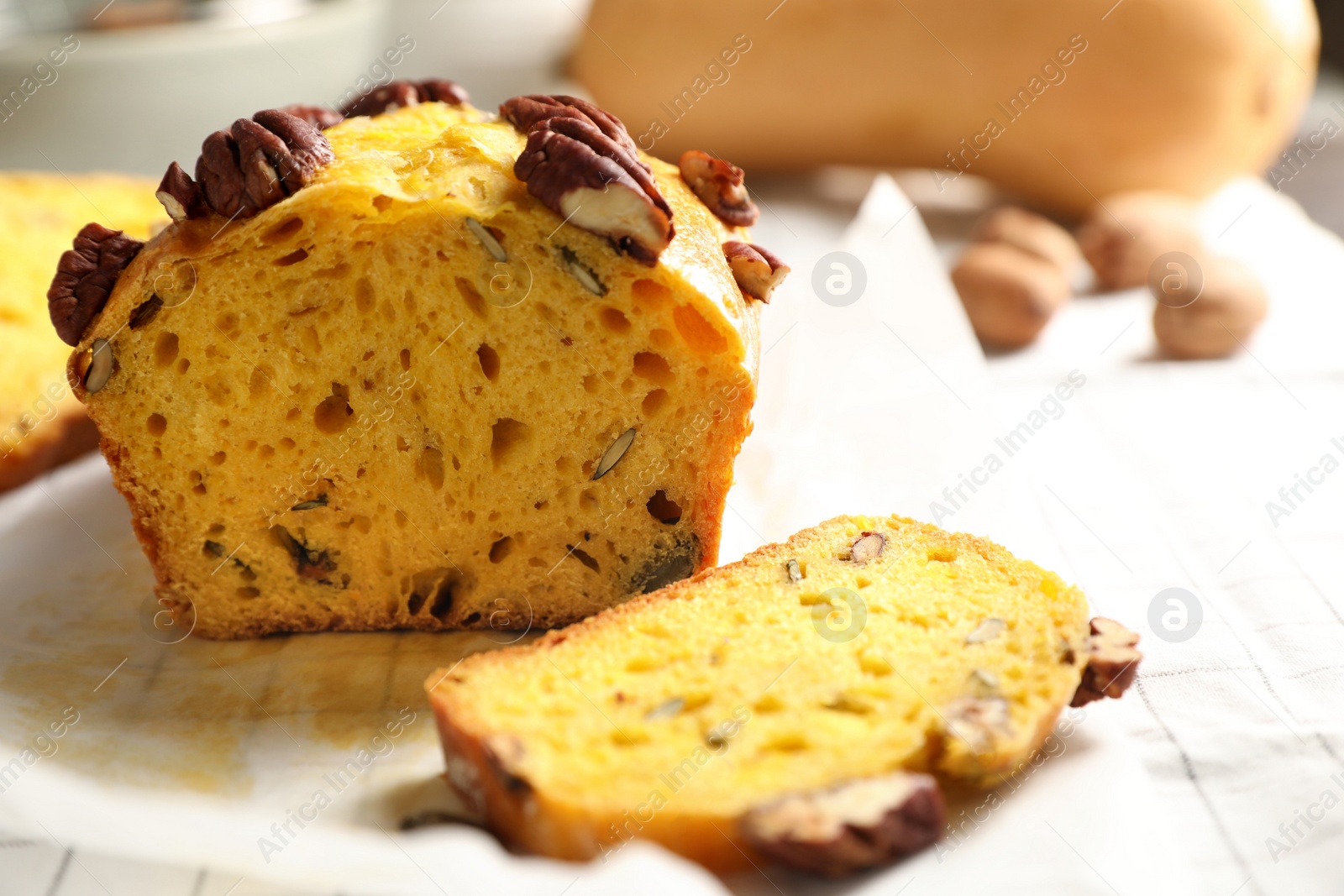 Photo of Delicious pumpkin bread with pecan nuts on tablecloth, closeup