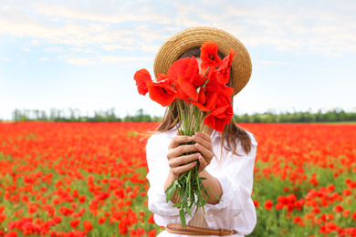 Woman with bouquet of beautiful poppy flowers in field