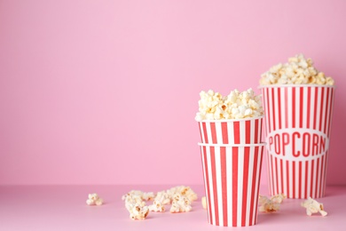 Photo of Tasty popcorn in paper cups on color background. Space for text