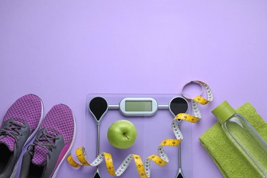 Flat lay composition with electronic scales and measuring tape on violet background, space for text